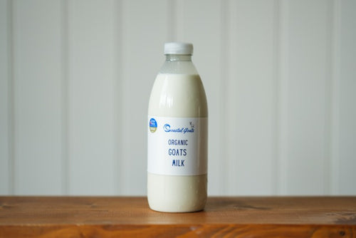Bottle of Organic Goats Milk on a wooden surface with a white background